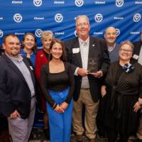 Bob Stoll smiles with his award surrounded by a group of supporters